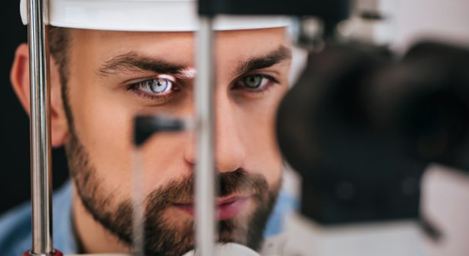 Man undergoing an eye examination using a slit lamp. Focus on the left eye.
