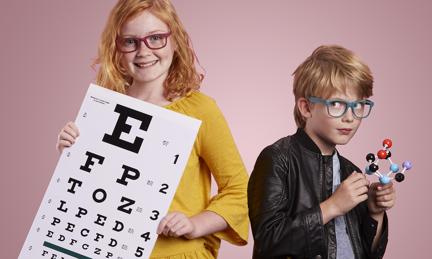 Girl with eye chart, letters: E, FP, TOZ, LPED, PECFD. Boy holding a molecular structure model.