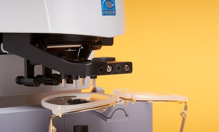 NIDEK optical machine aligning eyeglasses for lens processing.