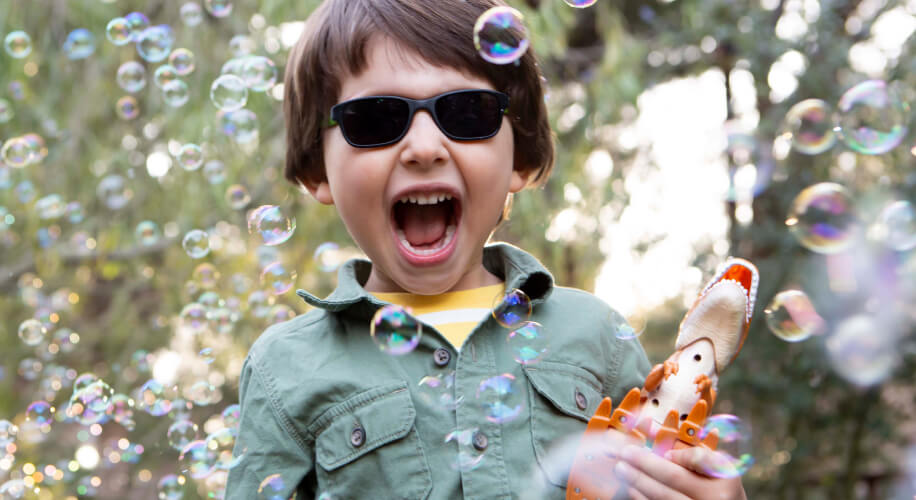 Kid playing with bubbles where kid sunglasses.