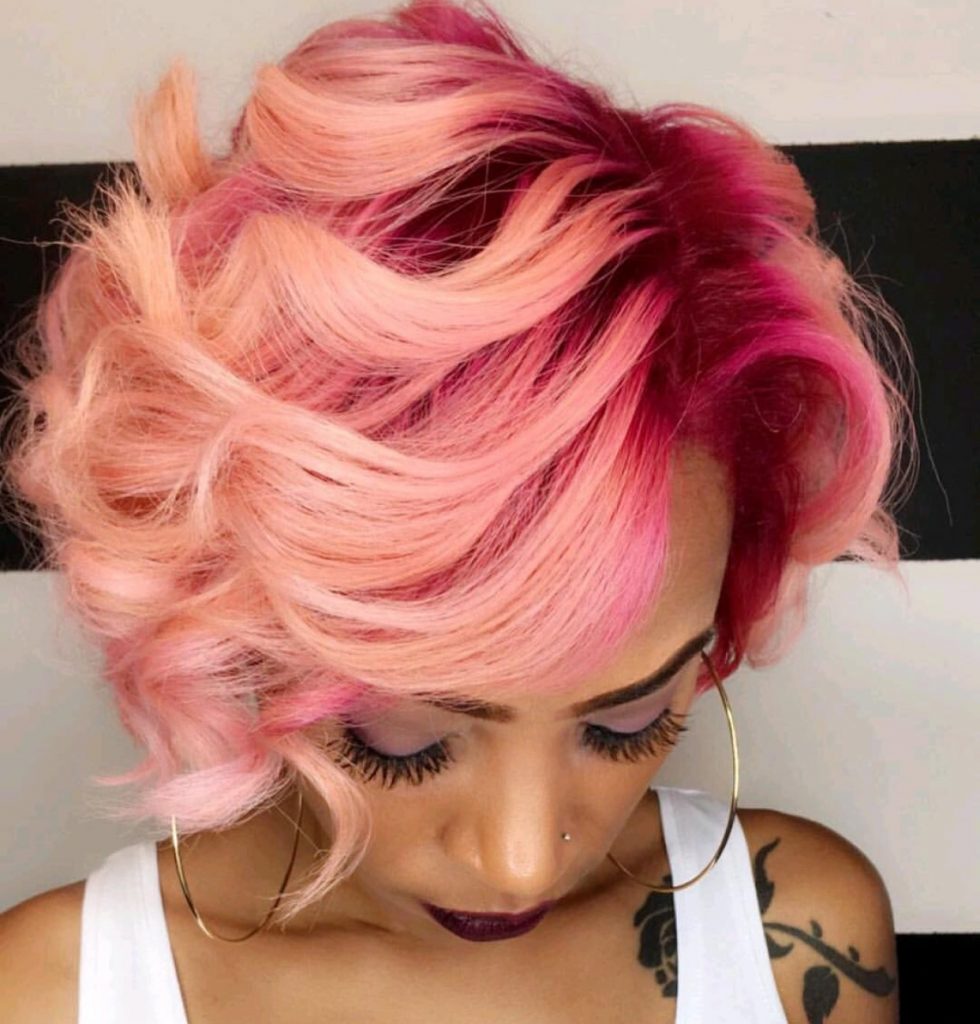 Short, curly hairstyle in shades of pink and rose gold.