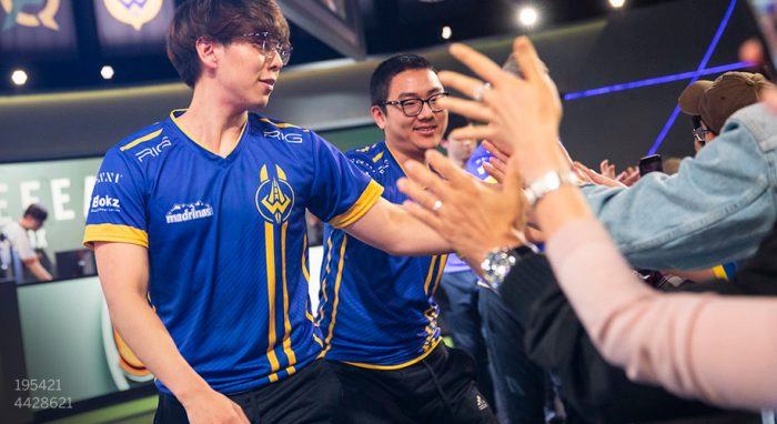 Two esports players in blue jerseys with yellow accents interacting with fans. Text: 195421, 4428621.