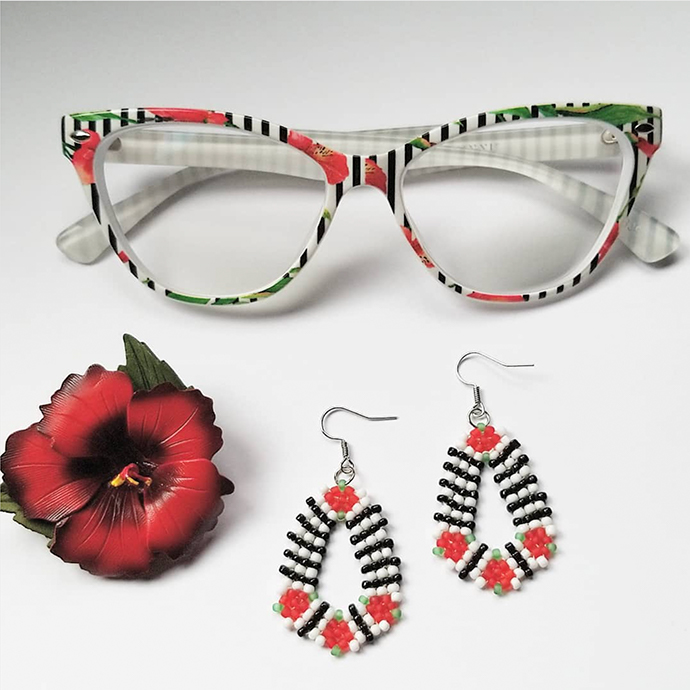 Colorful patterned glasses with red, white, and black beaded earrings and a red flower.