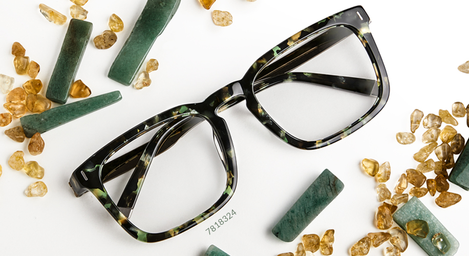 Tortoiseshell eyeglasses frame with product code 7818324, surrounded by green and amber stones.
