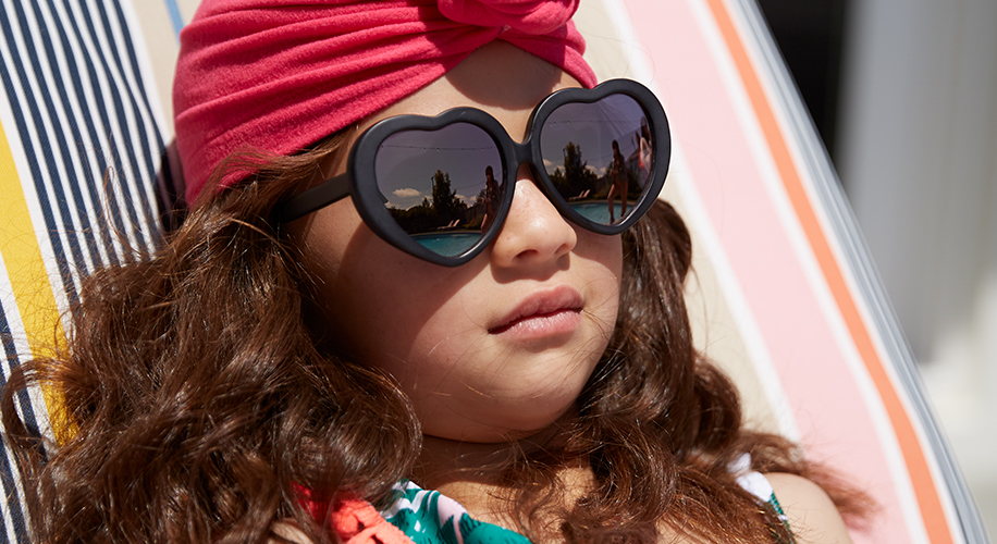 A little girl wears heart-shaped sunglasses.
