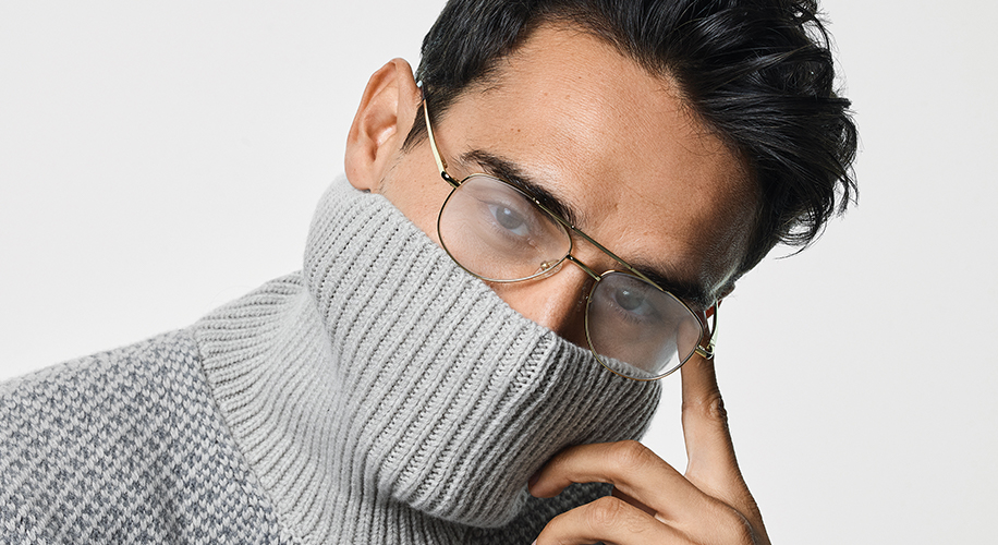 Man wearing gold wire-rimmed glasses and a gray high-collar knit sweater partially covering his face.