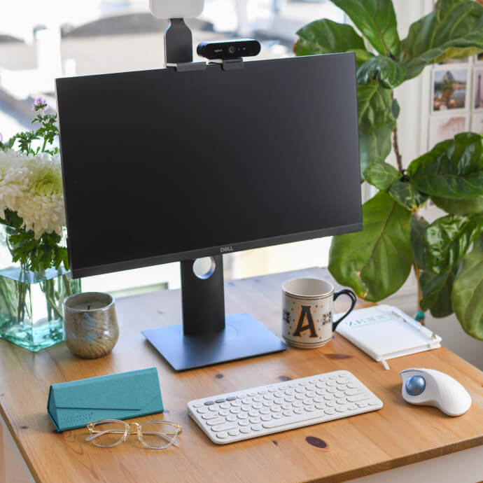 Dell monitor with attached webcam, keyboard, trackball mouse, and a mug with the letter &quot;A&quot; on the desk.