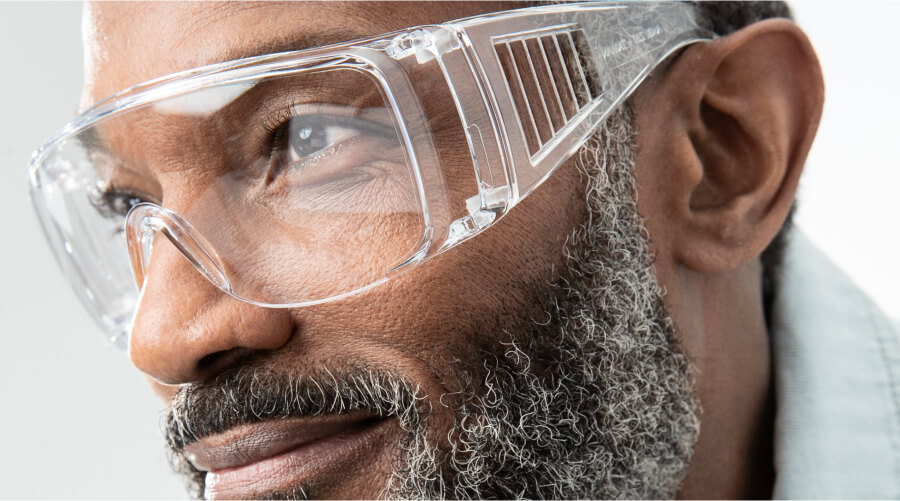 A middle-aged male model with black and gray beard wears clear Zenni safety glasses.