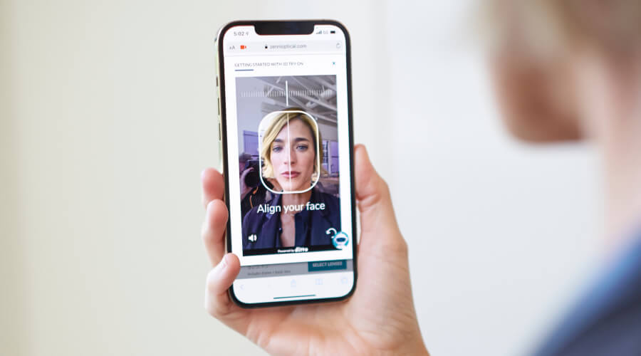 Woman holds iPhone in front of her face, so that the front-facing camera can scan her face shape for Zenni's Virtual Frame Try-On.