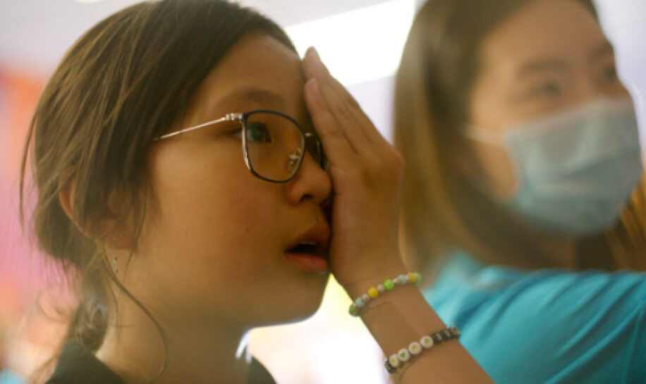 Zenni Volunteer Assists Young Girl With Eye Screening