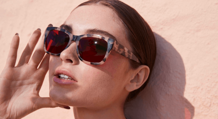 Woman wearing stylish, tortoiseshell-patterned sunglasses with red-tinted lenses.