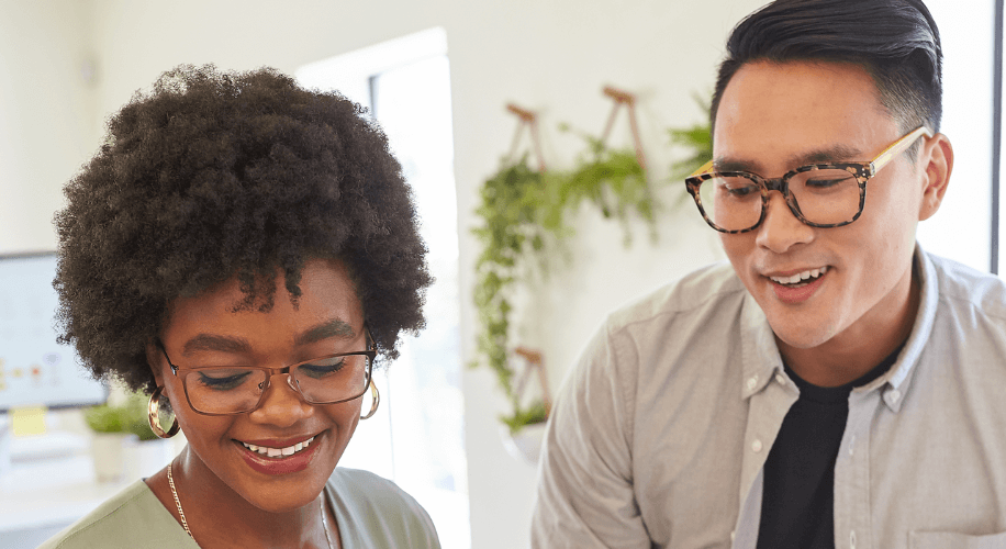 Two people wearing glasses, smiling and looking down.