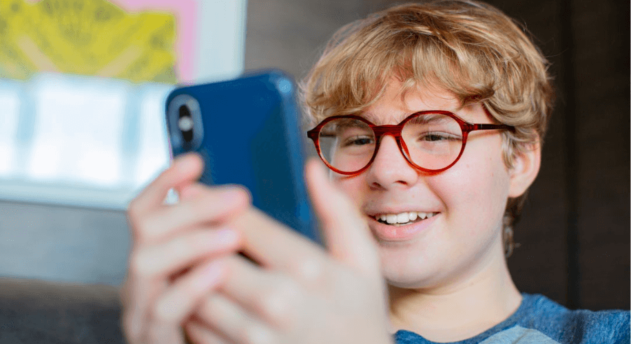 Young man reading his phone while wearing glasses.