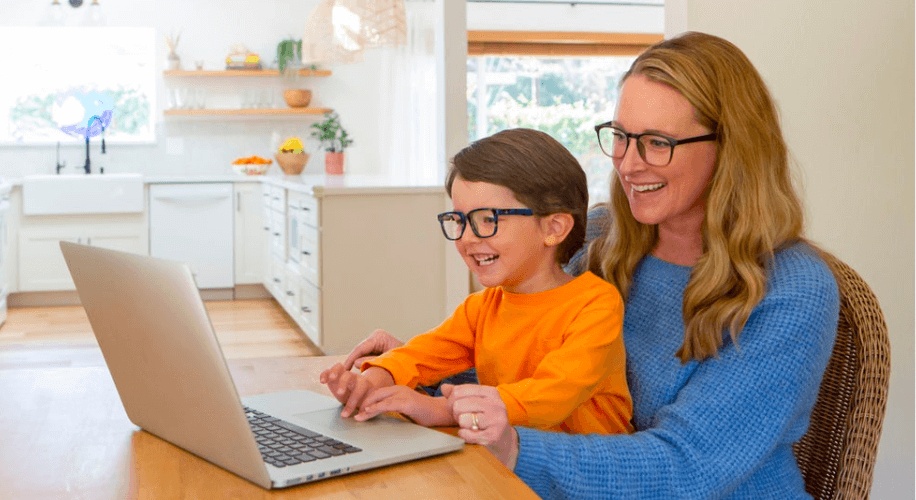 Woman and young boy both wearing glasses while using a computer.