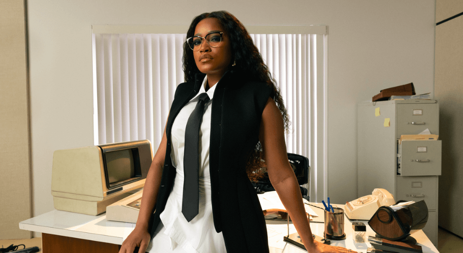 Image of Keke Palmer wears Zenni glasses and stands in front of a 70s style computer.