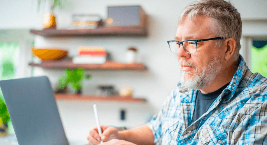 Man using a stylus pen and laptop, wearing glasses and a plaid shirt.