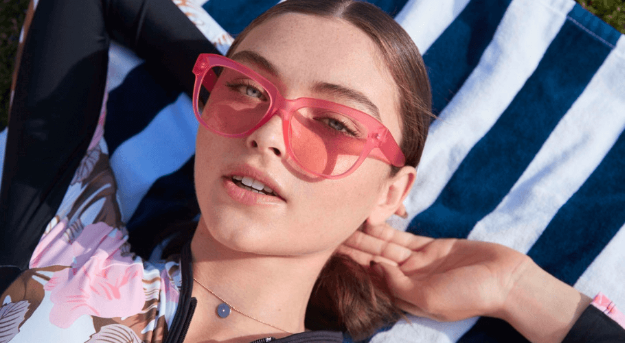 Person wearing pink sunglasses and a floral-patterned top.