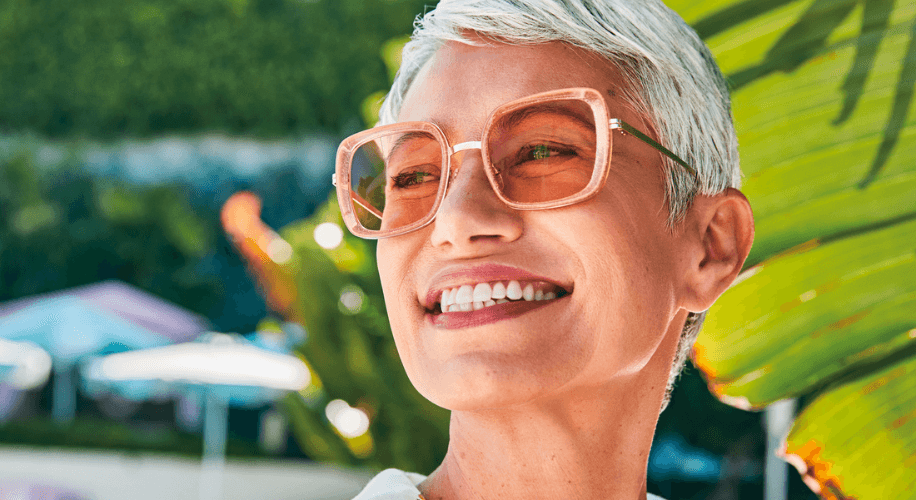 An older woman wears a pair of rose tinted eyeglasses.