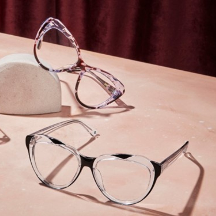 Two pairs of eyeglasses, one with black rims and the other with a marbled purple pattern on display.