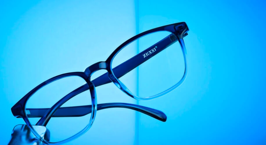 Black-framed ZENNI eyeglasses against a blue background.