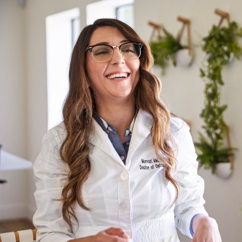 Smiling individual wearing eyeglasses and a white lab coat with the text "Marnvi Ahlawat, Doctor of Optometry".