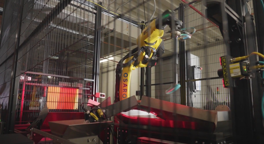 Robotic arm with &quot;OSARO&quot; and &quot;COGNEX&quot; labels in an industrial setting, handling a stainless steel container.