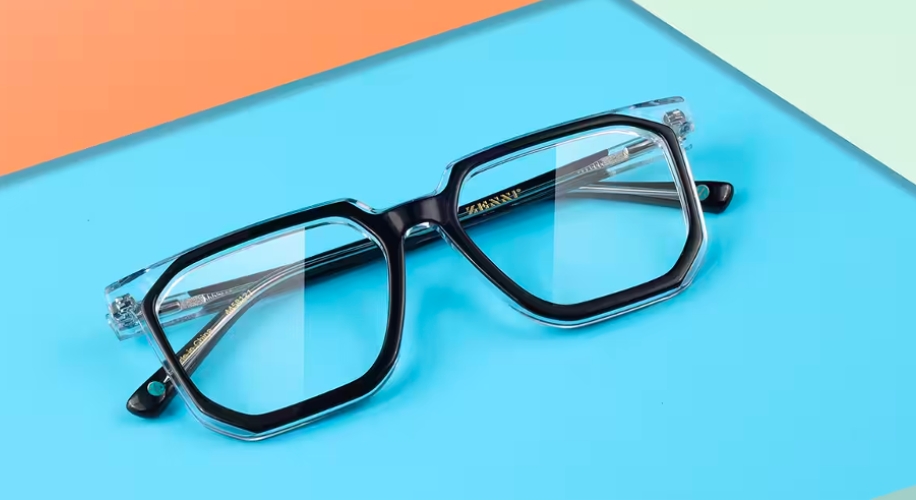 Black and clear square eyeglasses with transparent arms on a blue and peach background.