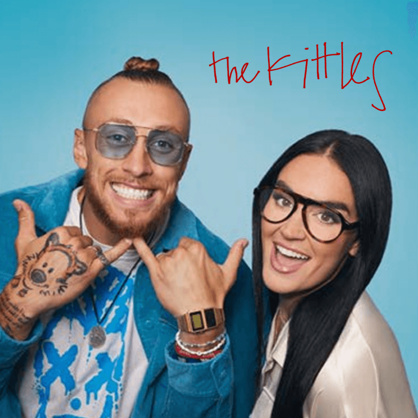 The Kittles: Person with glasses and tattoos smiling and gesturing with hands, next to smiling woman with glasses.