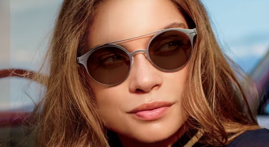 Woman wearing round, silver-framed sunglasses with brown lenses.
