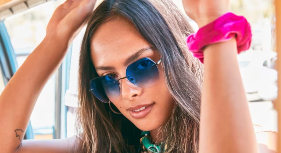 Woman wearing blue gradient sunglasses and a pink scrunchie.