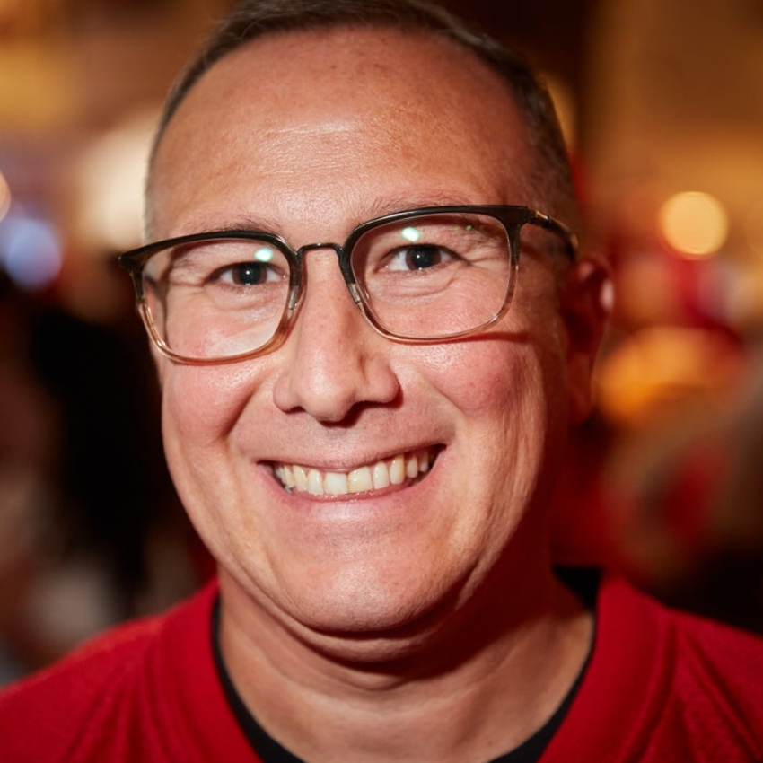 Smiling person wearing glasses and a red shirt.