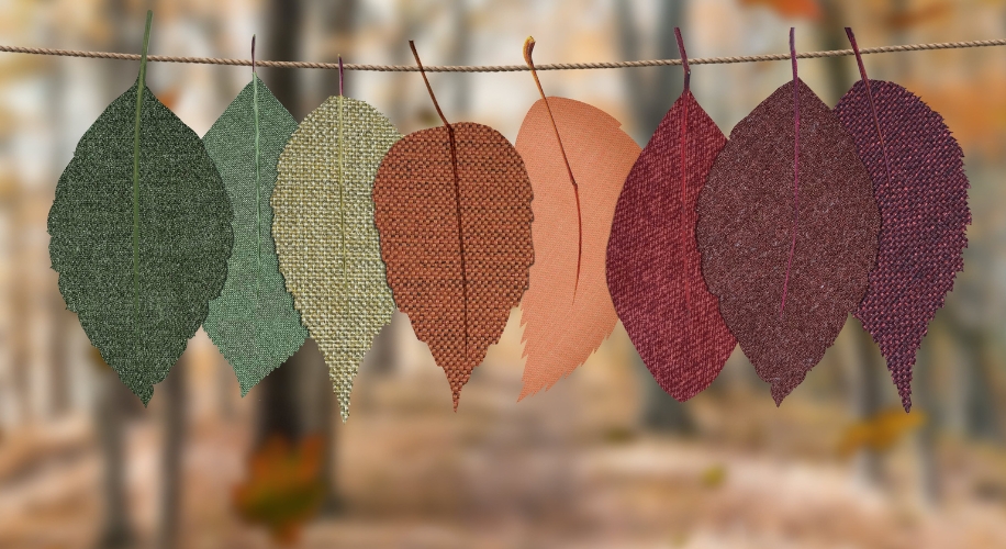 Colorful fabric leaves hanging on a string, in shades of green, orange, red, and maroon.