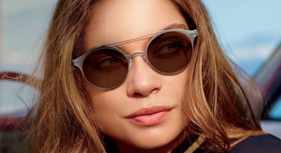 Woman wearing stylish round sunglasses with metal frame.
