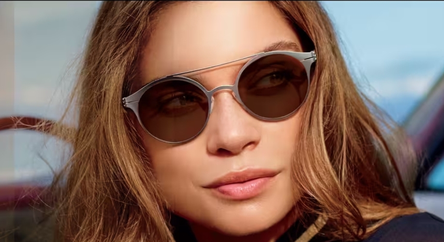 Woman wearing round, brown-tinted sunglasses with a sleek, silver frame.