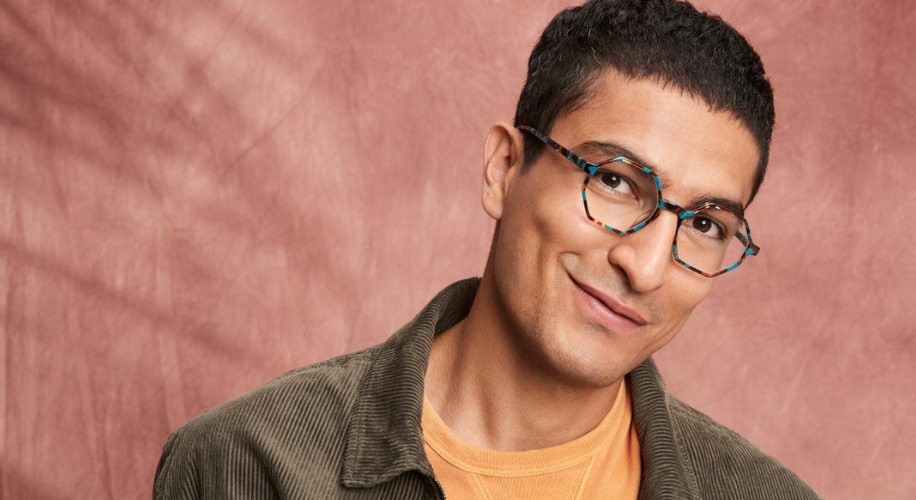 Person wearing blue tortoiseshell eyeglasses, corduroy jacket, and mustard yellow shirt.