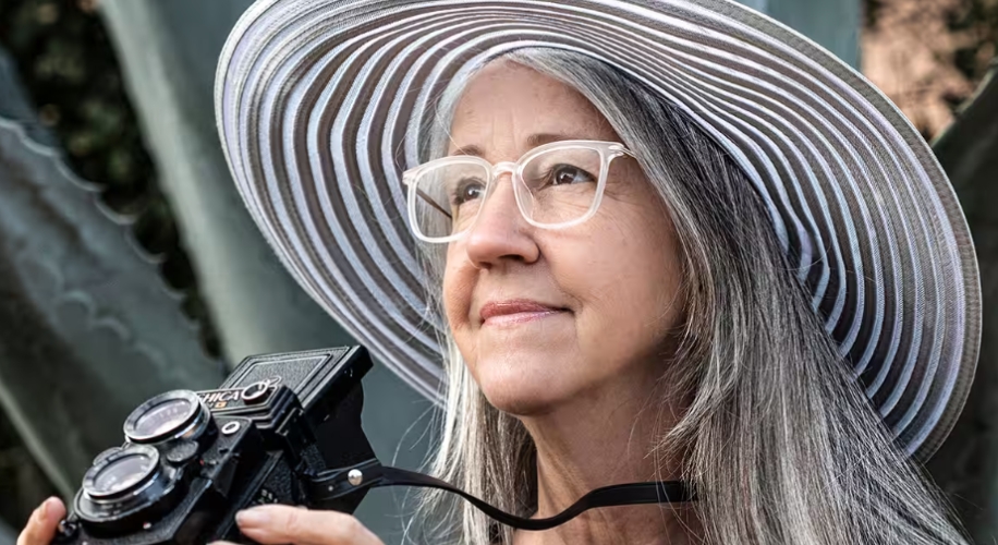 Woman in a striped sun hat holding a vintage Yashica film camera.