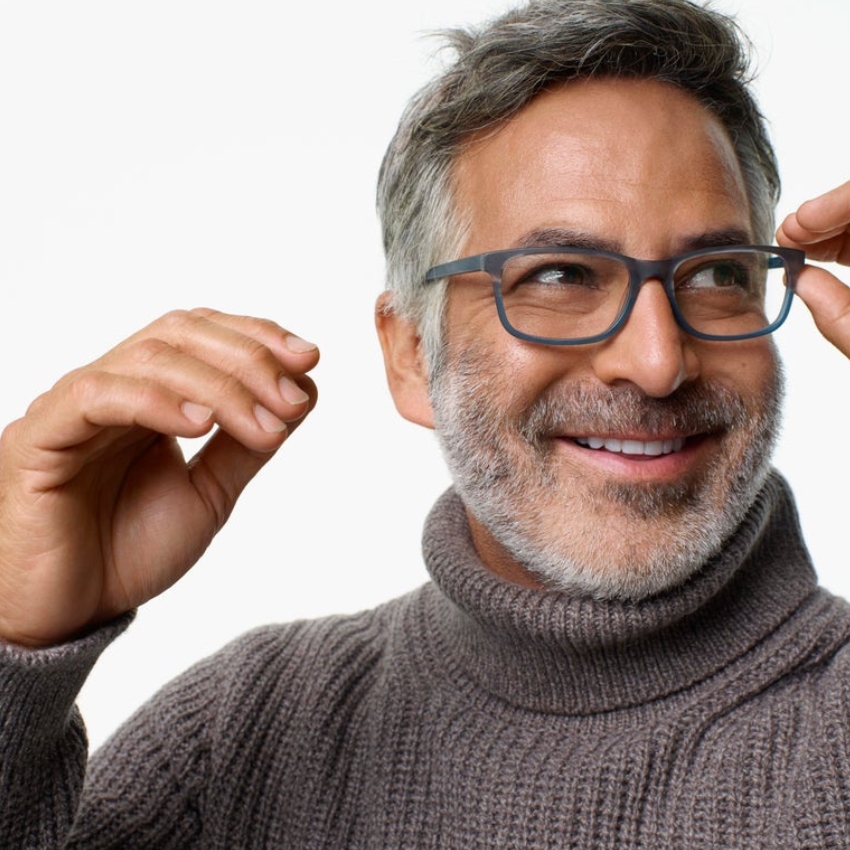 Man adjusting gray eyeglasses, wearing a gray knitted turtleneck sweater.