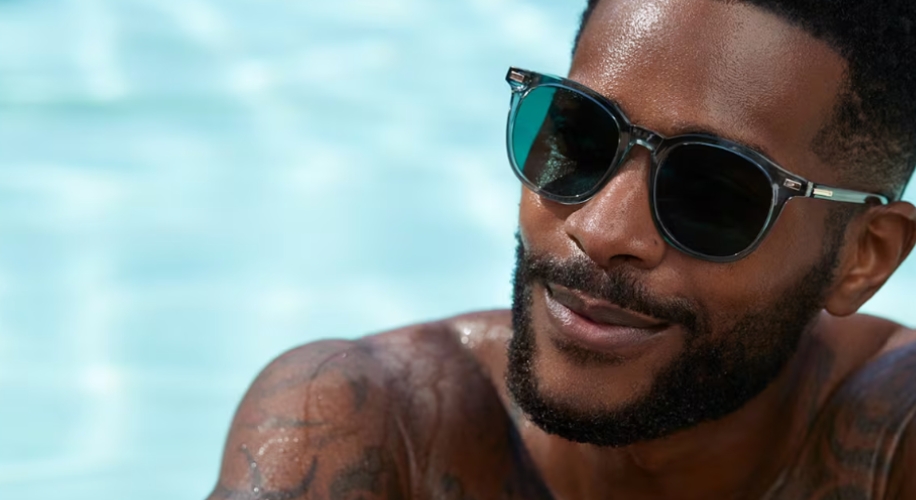 Person wearing sleek, black sunglasses with mirrored lenses and clear accents.
