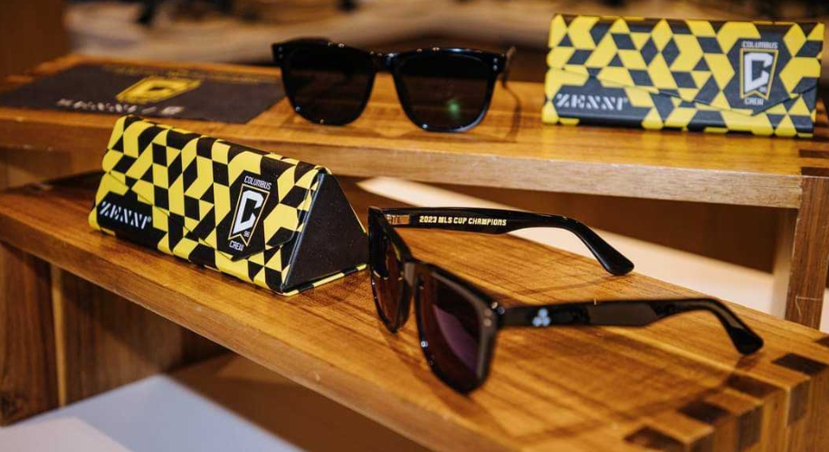 Columbus Crew Zenni sunglasses with black frames and yellow checkered box. Text: &quot;2020 MLS Cup Champions.&quot;