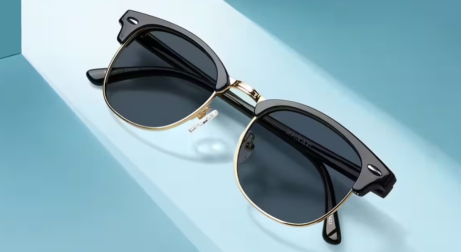 Black and gold sunglasses with dark lenses on a blue and white surface.