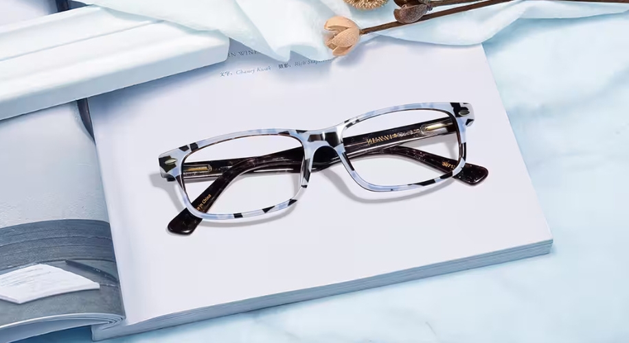 Tortoiseshell eyeglasses with rectangular lenses and black temples sitting on an open book.