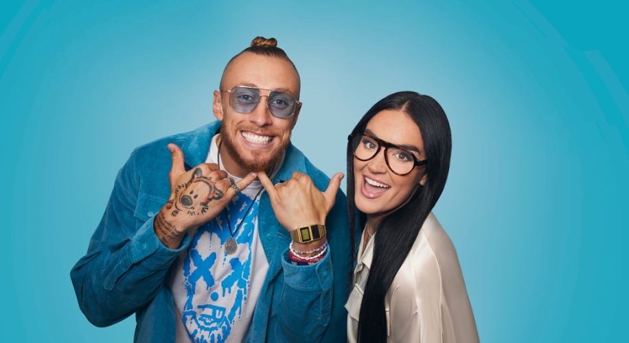 Man in blue jacket and sunglasses with thumbs up, woman in white top and glasses smiling.