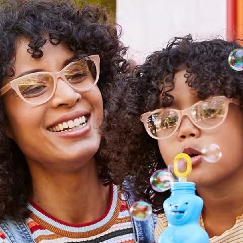 Adults' and kids' matching pink cat-eye glasses; child blowing bubbles using a blue bear-shaped bottle.