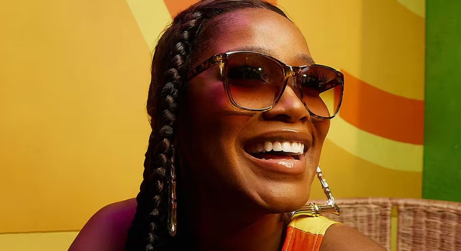 Person wearing oversized brown sunglasses with gradient tint. Large hoop earrings visible.