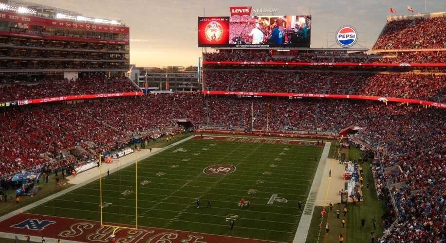 A packed stadium with Levi&#039;s Stadium and Pepsi logos. Large screen showing &quot;JOURNEY&quot; and stage performance.