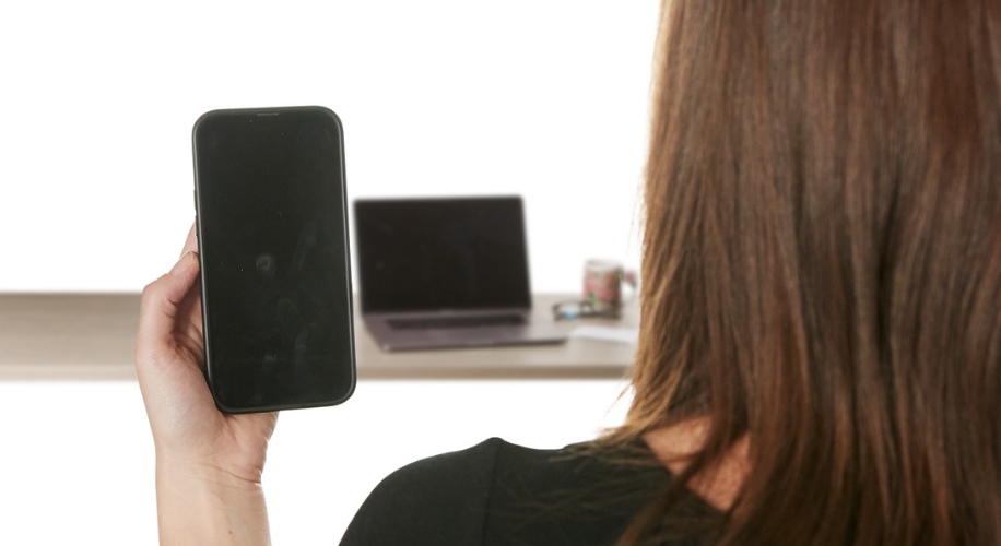 Person holding a black smartphone with a blank screen.