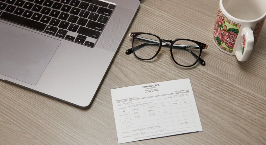 Laptop, eyeglasses, coffee mug, and prescription paper from Dr. John Doe, O.D. for Rickard D, Plano, TX.