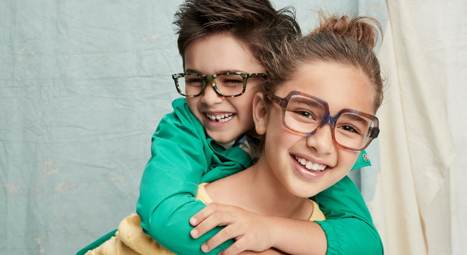 Children wearing colorful eyeglasses, smiling and laughing.