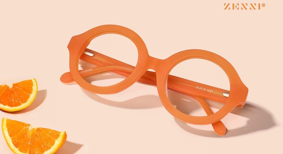 Orange round-framed Zenni glasses placed diagonally with text &quot;ZENNI&quot; on the side arm.