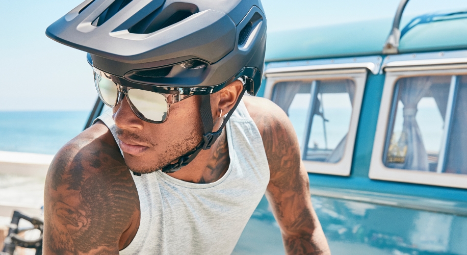 Man wearing a black cycling helmet and mirrored sunglasses.